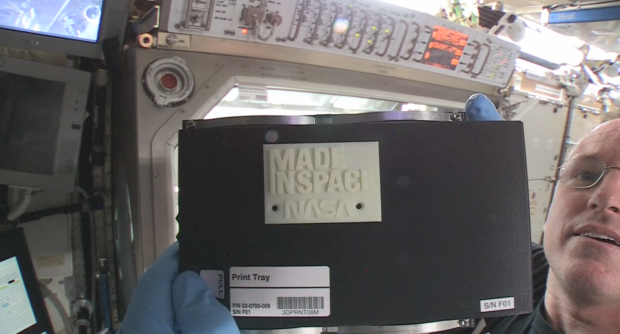 ISS Commander Barry “Butch” Wilmore holds up the first 3-D printed part made in space.